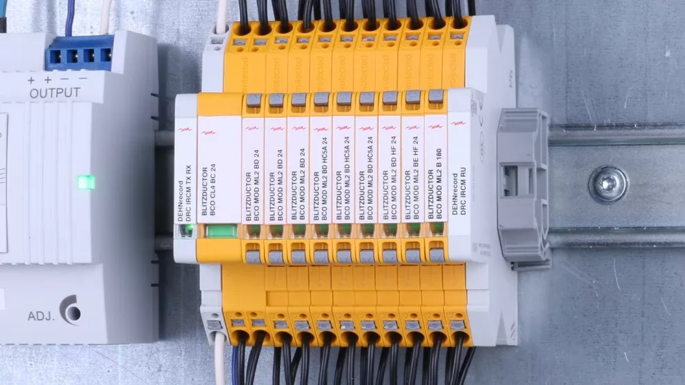 Mehrere gelbe Kombi-Ableiter, montiert und verkabelt auf Hutschiene, neben anderen Geräten im Schaltschrank.